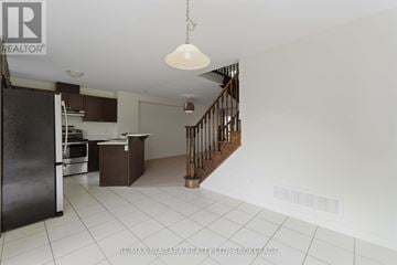 Thorold (Confederation Heights) townhouse for rent - A kitchen with a refrigerator, stove, and a counter with a hanging light fixture.