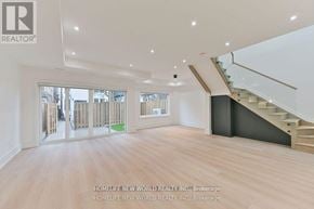 Toronto (Dufferin Grove) apartment for rent - A spacious room with wooden flooring and a staircase leading to another level.