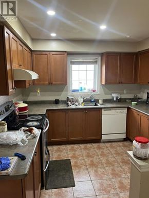 Brampton (Sandringham-Wellington) townhouse for rent - A kitchen with brown cabinets and a tiled floor.