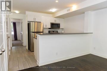 Kitchener townhouse for rent - A kitchen with white cabinets and a stainless steel refrigerator.
