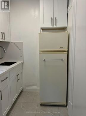Toronto (Casa Loma) multi-family for rent - A white refrigerator in a kitchen with white cabinets.