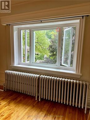 Toronto (Casa Loma) multi-family for rent - A white radiator is in front of a window with a view of trees.