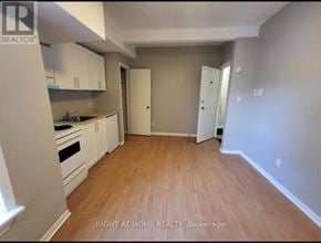 Toronto (South Riverdale) apartment for rent - A kitchen with white cabinets and a wooden floor.