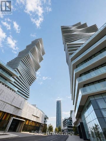 Mississauga (City Centre) condo for rent - A modern building with a curved facade stands tall against a blue sky.