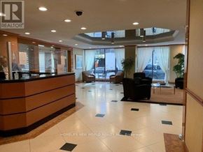 Toronto (Bay Street Corridor) condo for rent - A reception area with a brown reception desk and a man standing behind it.