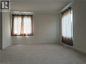 Ancaster townhouse for rent - A room with a carpeted floor and two windows with curtains.