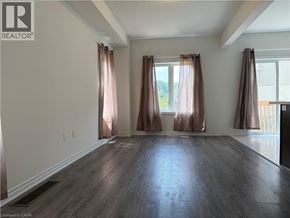 Ancaster townhouse for rent - A room with wooden floors and two windows with curtains.