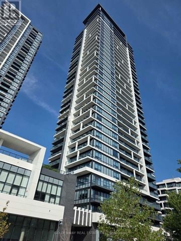 Markham (Unionville) condo for rent - A tall building with a glass facade stands in front of a clear blue sky.