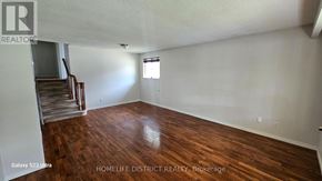 Oshawa (Centennial) apartment for rent - A room with wooden flooring and a staircase in the background.