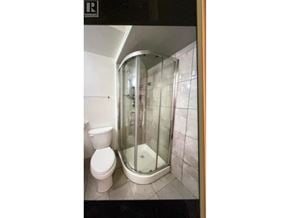Burnaby apartment for rent - A white toilet sits next to a walk-in shower.