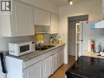 Burnaby apartment for rent - A kitchen with white cabinets and a black stove top.
