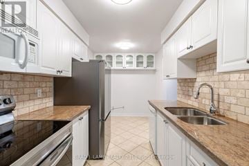 Mississauga (Mississauga Valleys) townhouse for rent - A kitchen with white cabinets and a brick wall.