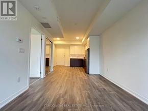 Toronto (Beechborough-Greenbrook) condo for rent - A spacious room with wood flooring and white walls.