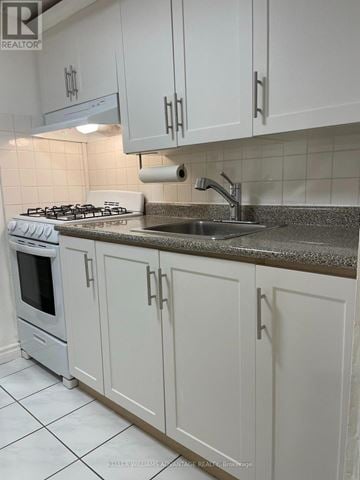 Toronto (Casa Loma) multi-family for rent - A kitchen with white cabinets and a granite countertop.