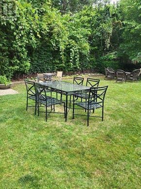 Toronto (Casa Loma) multi-family for rent - A glass table surrounded by chairs in a backyard.
