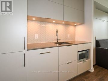 Toronto (Waterfront Communities) condo for rent - A modern kitchen with white cabinets and a wooden countertop.