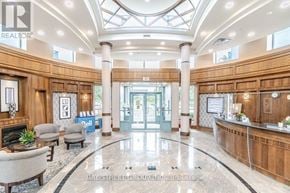 Mississauga (Central Erin Mills) condo for rent - A spacious lobby with a reception desk and a fireplace.