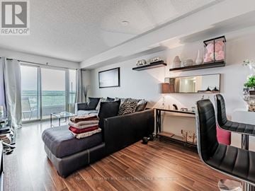 Pickering (Bay Ridges) condo for rent - A living room with a black couch and a large window.