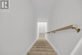Guelph (Clairfields/Hanlon Business Park) townhouse for rent - A staircase with a wooden handrail leads to a door at the end of the hallway.