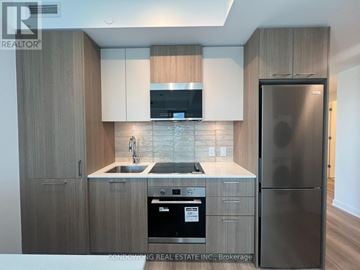Toronto (Regent Park) condo for rent - A modern kitchen with a stainless steel refrigerator and wooden cabinets.