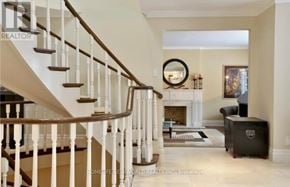 Toronto (St. Andrew-Windfields) apartment for rent - A staircase with white railings leads to a living room with a fireplace.