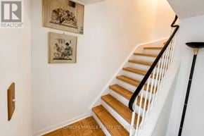 Mississauga (Meadowvale) townhouse for rent - A staircase with a wooden handrail and steps leading up to a landing with two pictures hanging on the wall.