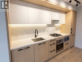 Vancouver apartment for rent - A modern kitchen with wooden cabinets and a white countertop.