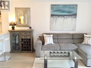 Burlington (Uptown) condo for rent - A grey couch with two pillows sits in front of a painting in a living room.