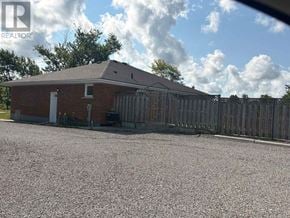 Niagara Falls (Schisler) apartment for rent - A house with a gravel driveway and a wooden fence.
