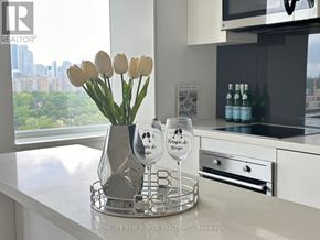 Toronto (Yonge-St. Clair) condo for rent - A vase with flowers and two wine glasses on a tray in a kitchen.