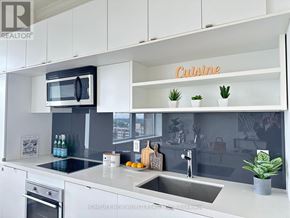Toronto (Yonge-St. Clair) condo for rent - A modern kitchen with a white color scheme and a shelf with the word "Cuisine" on it.