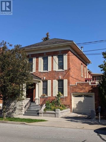 St. Catharines (Downtown) fourplex for rent - A red brick house with a white garage door.
