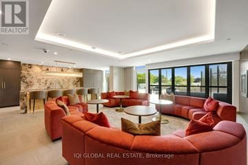 Guelph (St. Patrick's Ward) condo for rent - A modern living room with red sofas and a stone wall.