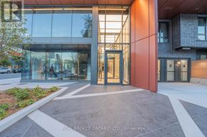 Toronto (Moss Park) condo for rent - The image shows the front of a building with a glass facade and a red pillar with the number 28 on it.