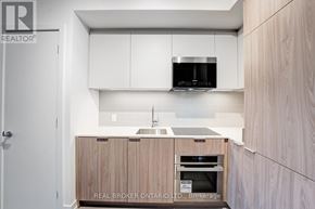 Toronto (Moss Park) condo for rent - A modern kitchen with wooden cabinets and a white countertop.
