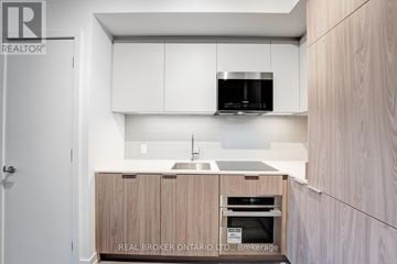 Toronto (Moss Park) condo for rent - A modern kitchen with wooden cabinets and a white countertop.