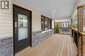 Welland apartment for rent - A wooden deck leads to a house with a stone wall and a glass door.