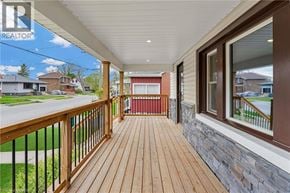 Welland apartment for rent - A wooden deck with a railing and a view of a street with houses.