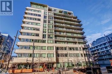 Toronto (Waterfront Communities) condo for rent - A tall building with many windows is under a blue sky.