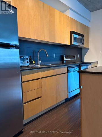Toronto (Waterfront Communities) condo for rent - A kitchen with wooden cabinets and a stainless steel refrigerator.