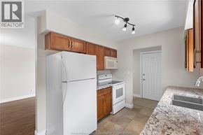 Windsor apartment for rent - A kitchen with a white refrigerator, wooden cabinets, and a marble countertop.