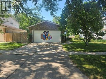 Windsor apartment for rent - A garage with a mural on the door is surrounded by a well-kept lawn and trees.