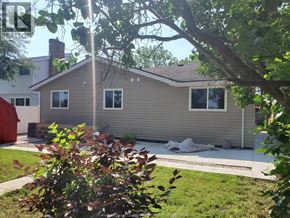 Windsor apartment for rent - A house with a grey siding and a brown roof is surrounded by greenery.