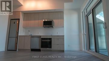 Toronto (Clairlea-Birchmount) condo for rent - A modern kitchen with wooden cabinets and a flat screen TV mounted above the island.