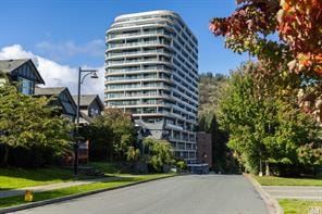 Victoria apartment for rent - A tall building with many windows is surrounded by trees and houses.