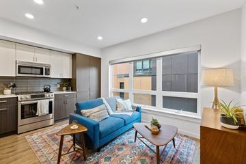 Seattle apartment for rent - A blue couch sits in a living room with a wooden coffee table in front of it.