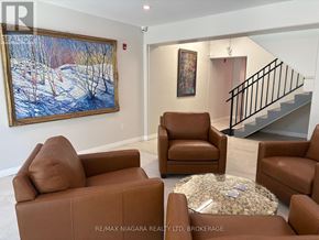 Fort Erie (Ridgeway) condo for rent - A living room with brown leather furniture and a painting on the wall.