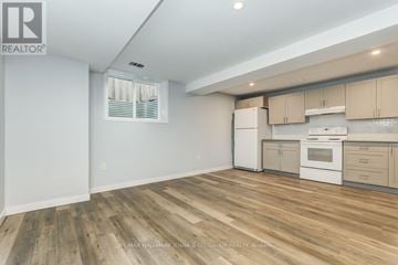 Ottawa apartment for rent - A well-lit kitchen with white appliances and wooden flooring.