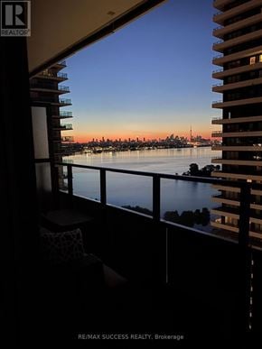 Toronto (Mimico) condo for rent - A balcony overlooks a body of water with a city skyline in the distance.