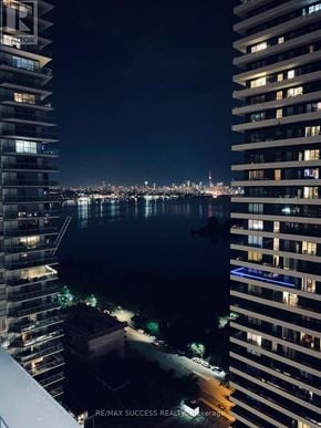 Toronto (Mimico) condo for rent - A night view of a cityscape with a body of water and buildings with lit windows.